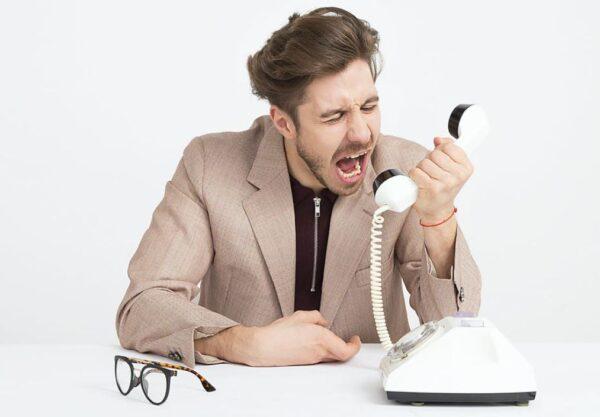 Ein frustrierter Mann schreit in den Telefonhörer. Effektive Kommunikationsstrategien im Kundenservice können solche Situationen verhindern.