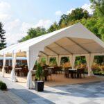 Festzelt mit weißer Plane, offener Seitenwand und Bestuhlung auf einer Terrasse bei Sonnenschein