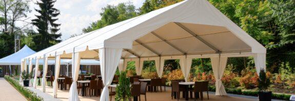 Festzelt mit weißer Plane, offener Seitenwand und Bestuhlung auf einer Terrasse bei Sonnenschein