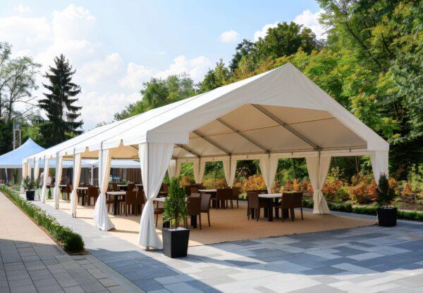 Festzelt mit weißer Plane, offener Seitenwand und Bestuhlung auf einer Terrasse bei Sonnenschein